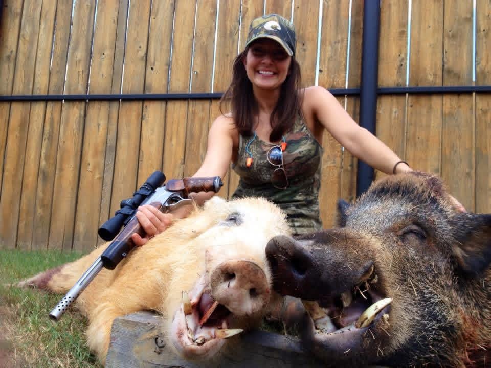 A hunter sharing a field moment beside two wild hogs