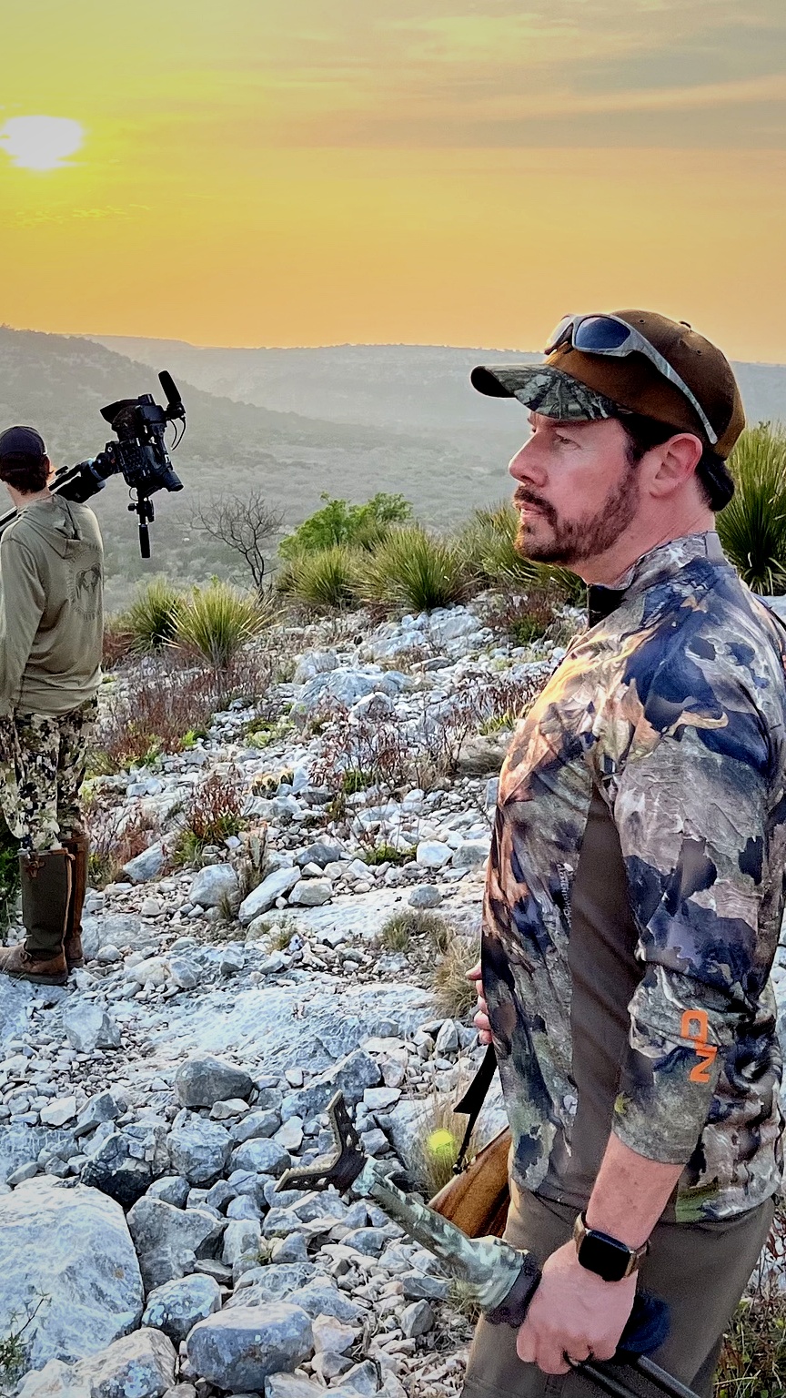 A hunter standing in the field at sunset